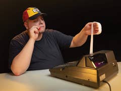 Une personne portant une casquette examine un long reçu sortant d'une caisse enregistreuse.