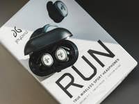 Écouteurs de sport sans fil dans un étui de chargement sur une boîte portant l'inscription 'RUN'.