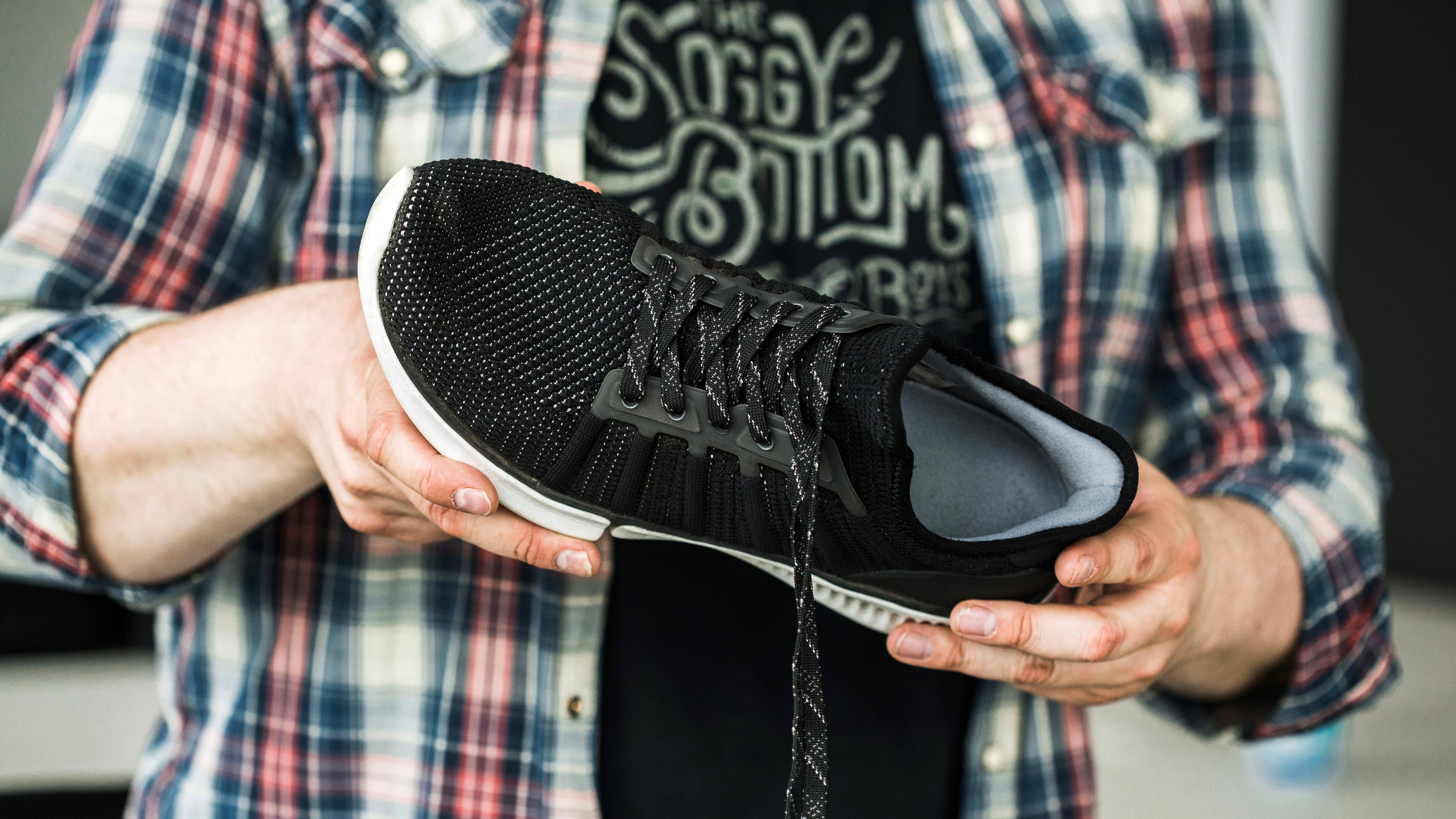 Une personne tenant une chaussure intelligente Xiaomi noire devant elle.