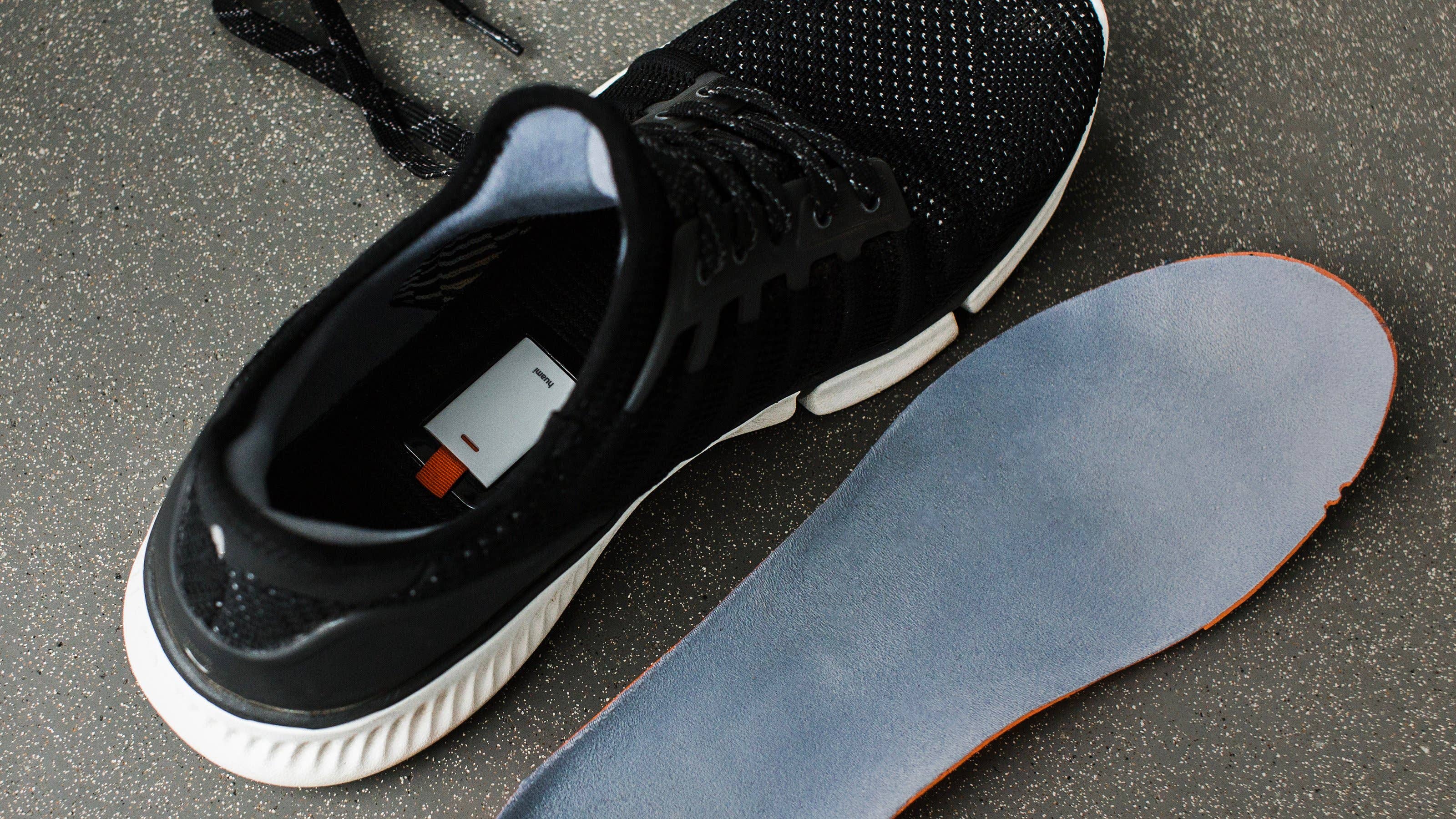 Chaussures Xiaomi noires avec semelle intérieure amovible sur une surface texturée.