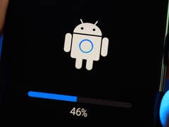 Une main tenant un smartphone affichant un écran de mise à jour Android avec un progrès de 46%.