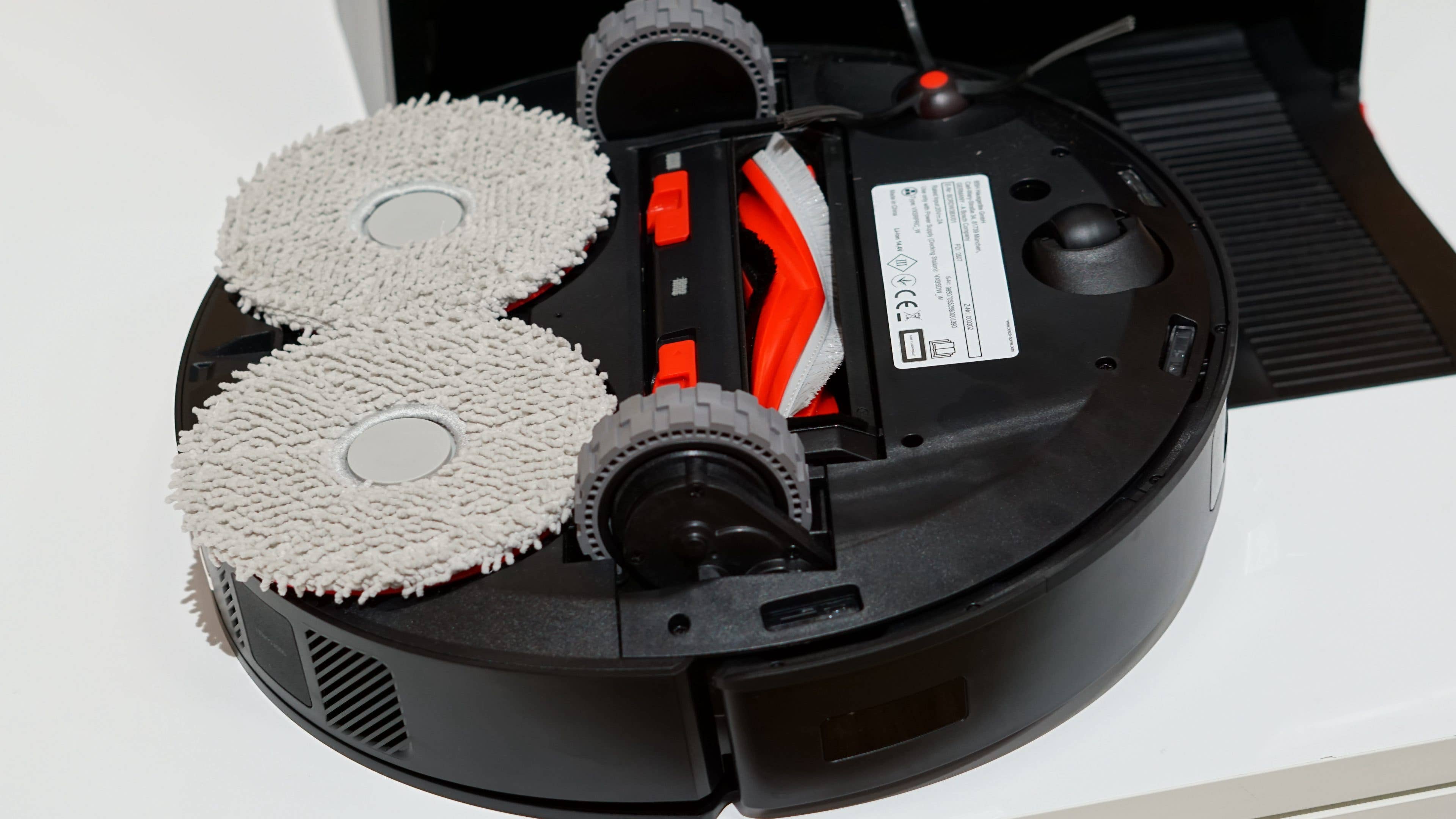 Aspirateur robot avec deux tampons de nettoyage et panneau de contrôle visible.