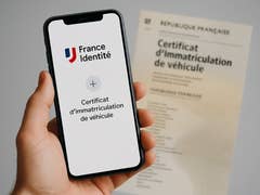 Un smartphone affichant un certificat d'immatriculation de véhicule numérique à côté d'un document imprimé.