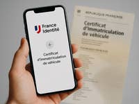 Un smartphone affichant un certificat d'immatriculation de véhicule numérique à côté d'un document imprimé.