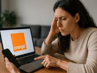 Femme stressée utilisant un ordinateur portable et un smartphone affichant le logo Orange.