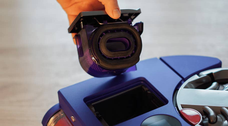 Une main tenant un filtre au-dessus de lu0027aspirateur Dyson 360 Vis Nav.