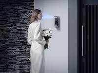 Une femme en robe blanche se tient près de l'appareil EZVIZ HP7 Pro, tenant un bouquet de fleurs.