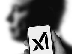 Une main tenant un smartphone affichant le logo 'X' devant une silhouette humaine floue.