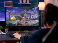 Une personne joue à un jeu de combat sur un ordinateur avec un clavier, affichant l'action à l'écran.