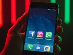 Une main tenant un smartphone affichant Facebook, Instagram, WhatsApp et d'autres applications à l'écran.