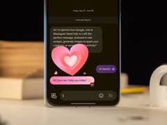 Un smartphone affichant une conversation dans Google Messages avec un message de salutation et des émojis de cœur.