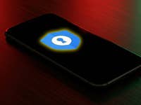 Un smartphone affiche le logo de Google Password Manager sur un fond sombre.