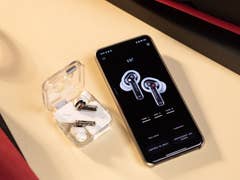 Les écouteurs sans fil Nothing Ear à côté d'un smartphone affichant l'application Nothing X