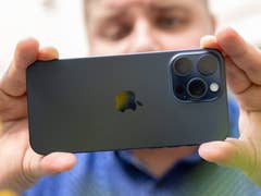 L'iPhone 15 Pro Max d'Apple tenu à deux mains horizontalement par Antoine et vu de dos