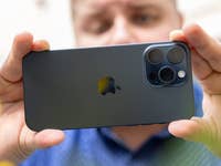 L'iPhone 15 Pro Max d'Apple tenu à deux mains horizontalement par Antoine et vu de dos