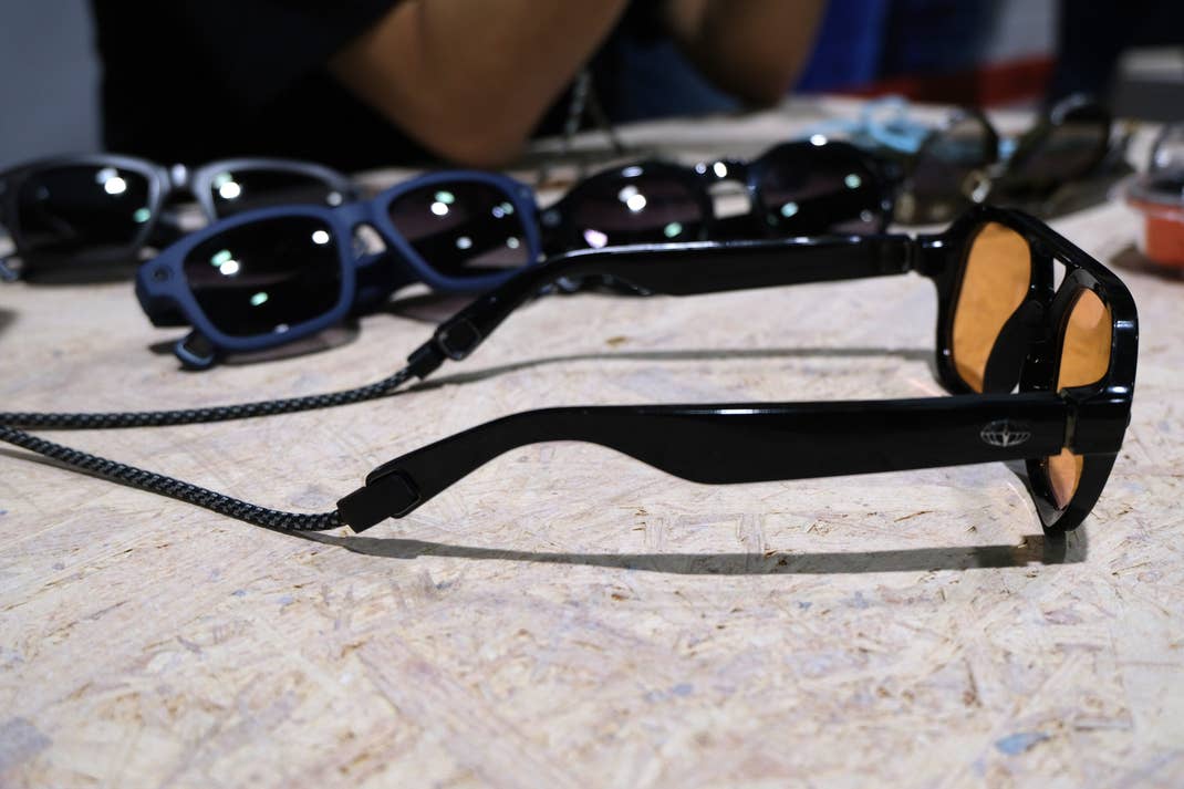 Une paire de lunettes de soleil noires avec des verres orange, posée sur une surface en bois parmi d