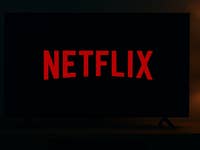 Une pièce sombre avec une télévision affichant le logo Netflix en rouge.