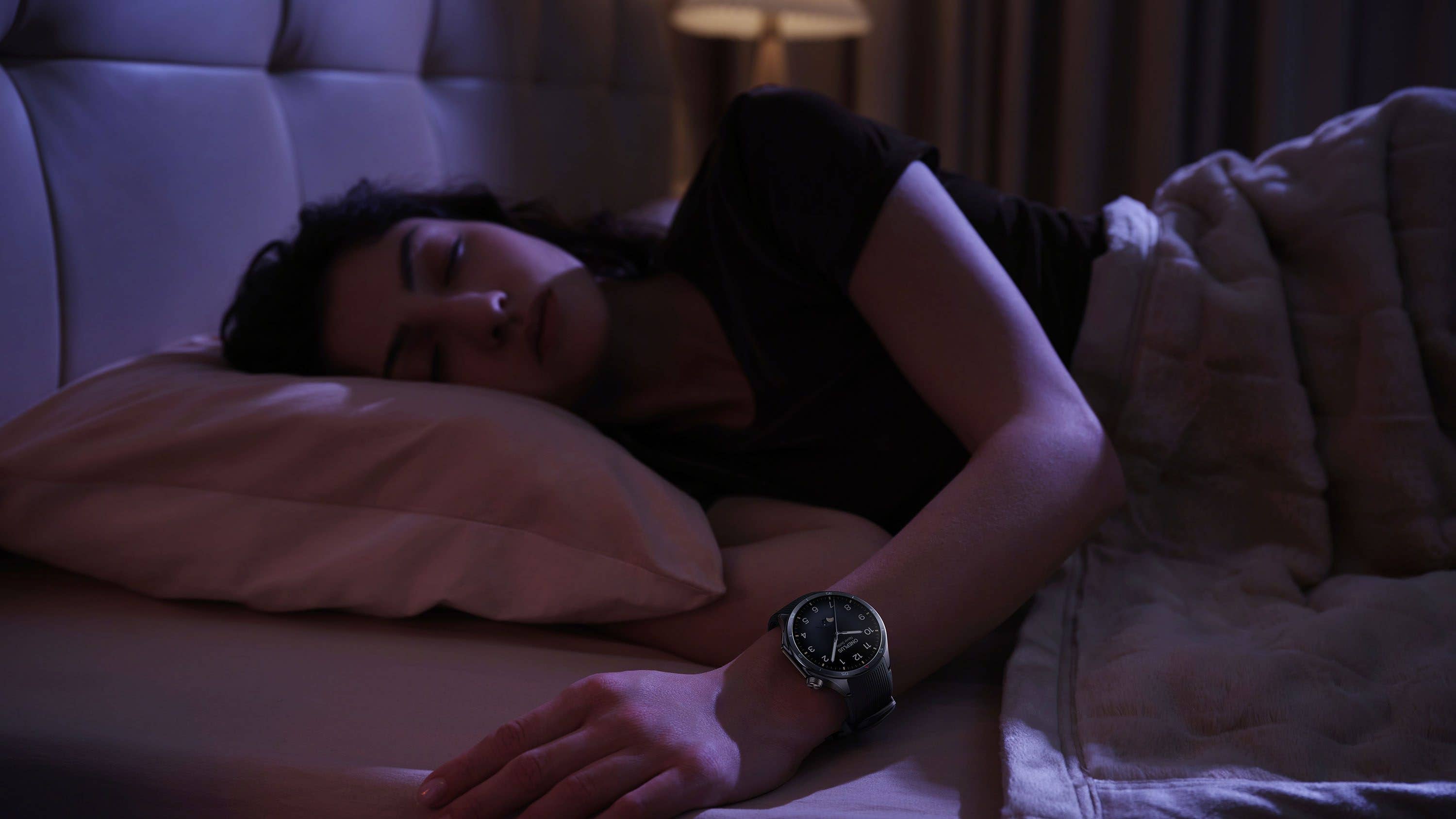 Une personne dort sur un lit, portant une OnePlus Watch 3 au poignet.