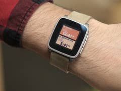 Un poignet portant une montre intelligente Pebble Time affichant l'heure et le lieu.