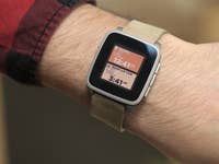 Un poignet portant une montre intelligente Pebble Time affichant l'heure et le lieu.