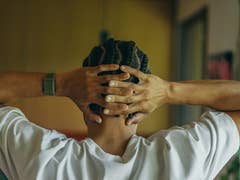 Une personne avec des cheveux tressés, portant un Polar Loop, repose les mains derrière la tête dans une pose détendue.