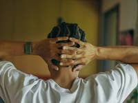 Une personne avec des cheveux tressés, portant un Polar Loop, repose les mains derrière la tête dans une pose détendue.