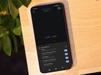 Un smartphone affichant 'Hello_Jade' et les fonctionnalités de 'Gemini Advanced' sur une table en bois.