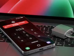 Un smartphone affichant un avertissement 'Tentative d'accès non autorisé' à côté d'un cadenas sur un clavier d'ordinateur portable.