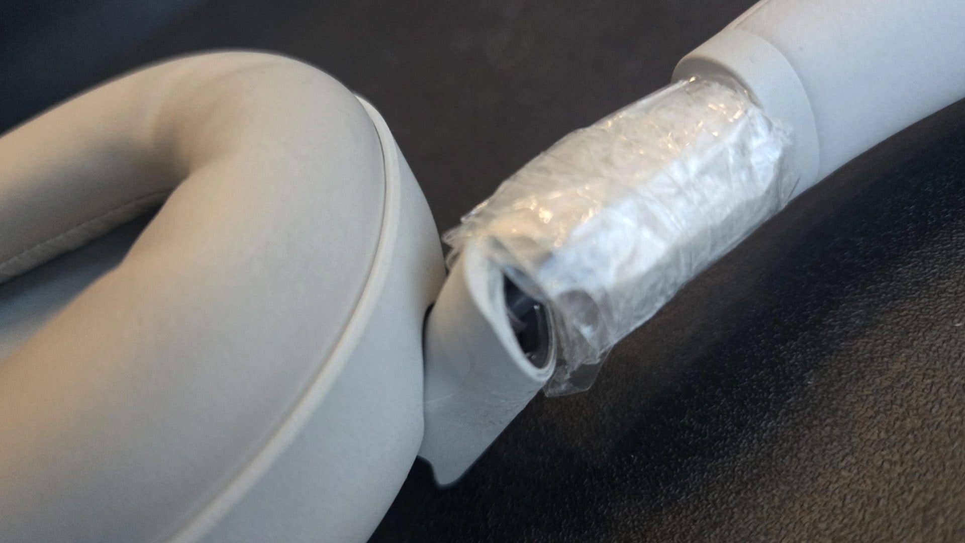 Gros plan sur des écouteurs Sony WH-1000XM6 avec un coussin d'oreille blanc et une partie du bandeau recouverte de ruban adhésif.