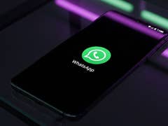 Un smartphone affichant le logo WhatsApp sur un écran noir.