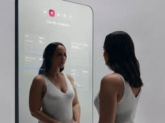 Une femme interagit avec le miroir intelligent Withings OMNIA affichant des données d'analyse cardiaque.