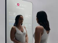 Une femme interagit avec le miroir intelligent Withings OMNIA affichant des données d'analyse cardiaque.
