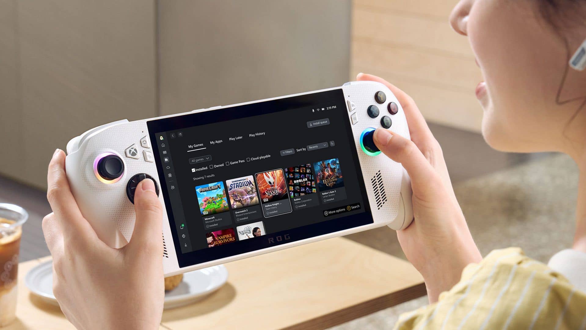 Une personne tient un appareil de jeu affichant l'interface Xbox avec des options de jeux.