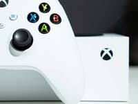 Un contrôleur Xbox blanc avec des boutons colorés à côté d'une boîte Xbox.