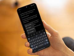Une personne tenant un smartphone affichant un tutoriel de notes avec des fonctionnalités IA telles que le résumé et la correction.