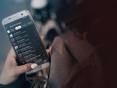 Une main tenant un smartphone affichant l'application YouTube Music Premium avec une playlist intitulée 'music for the gym'.