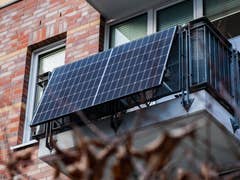 Des panneax solaires rigides accrochés sur le balcon d'un appartement vus de l'extérieur et d'en bas