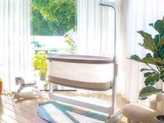 Un berceau moderne de bébé de Bosch dans une pièce lumineuse avec de grandes fenêtres, des plantes et un fauteuil confortable.