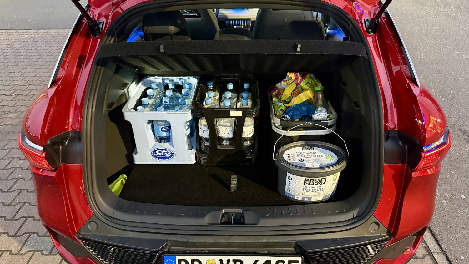 Le coffre d'une BYD Atto 3 rouge rempli de caisses d'eau et de collations.