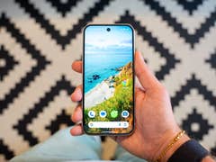 Une main tenant un smartphone Google Pixel 9 affichant un fond d'écran de plage.