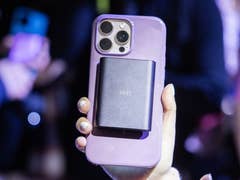 Une personne tenant un smartphone avec un accessoire noir attaché à l'arrière dans un cadre bondé.