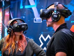 Deux personnes portant des casques de réalité virtuelle s'engagent dans une expérience de réalité virtuelle sur fond numérique.