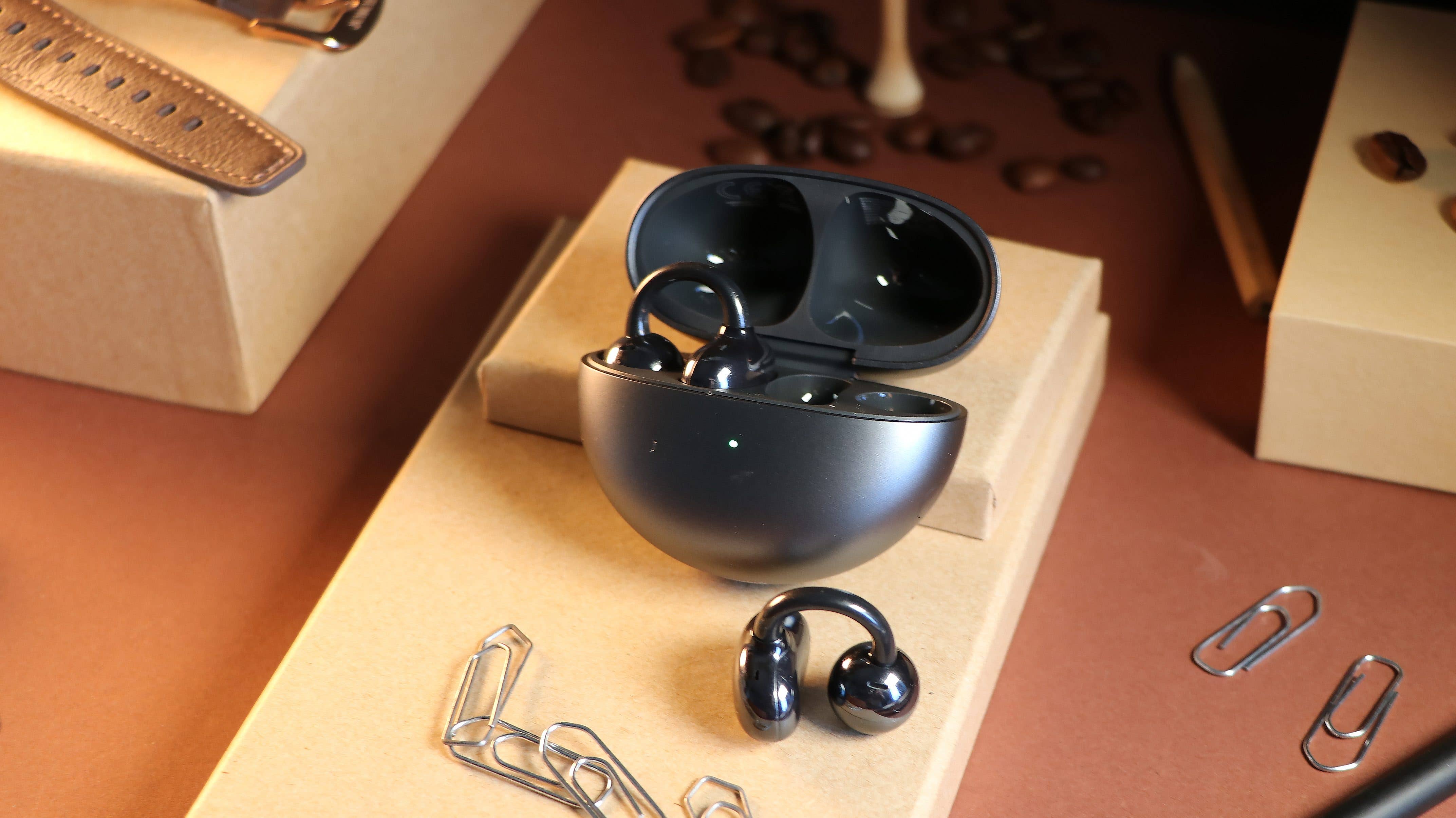 Un des écouteurs Huawei FreeClip posé devant le boîtier de recharge au couvercle ouvert et dans lequel se trouve l'autre écouteur