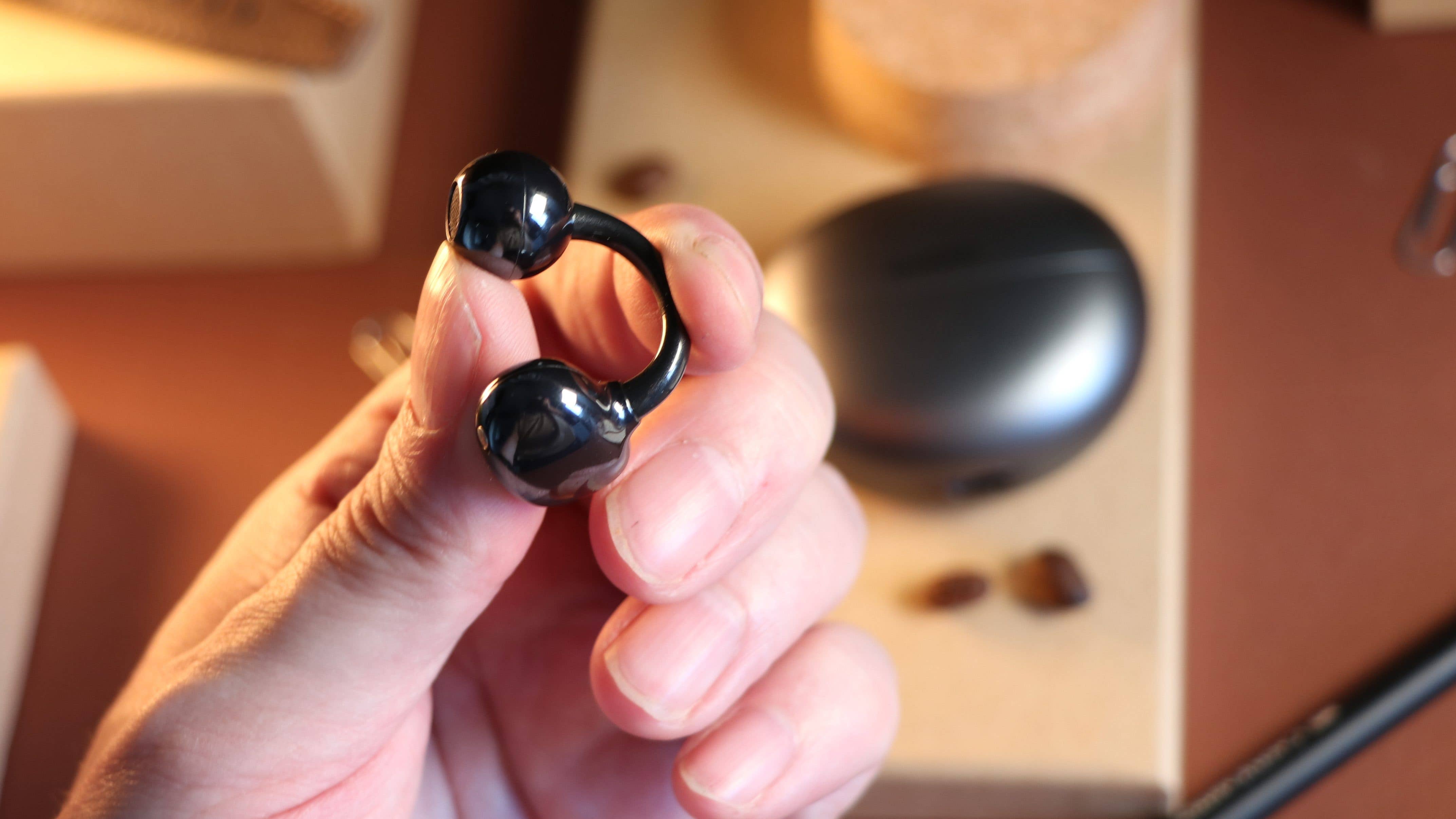 Un des écouteurs Huawei FreeClip vu de près et tenu dans une main