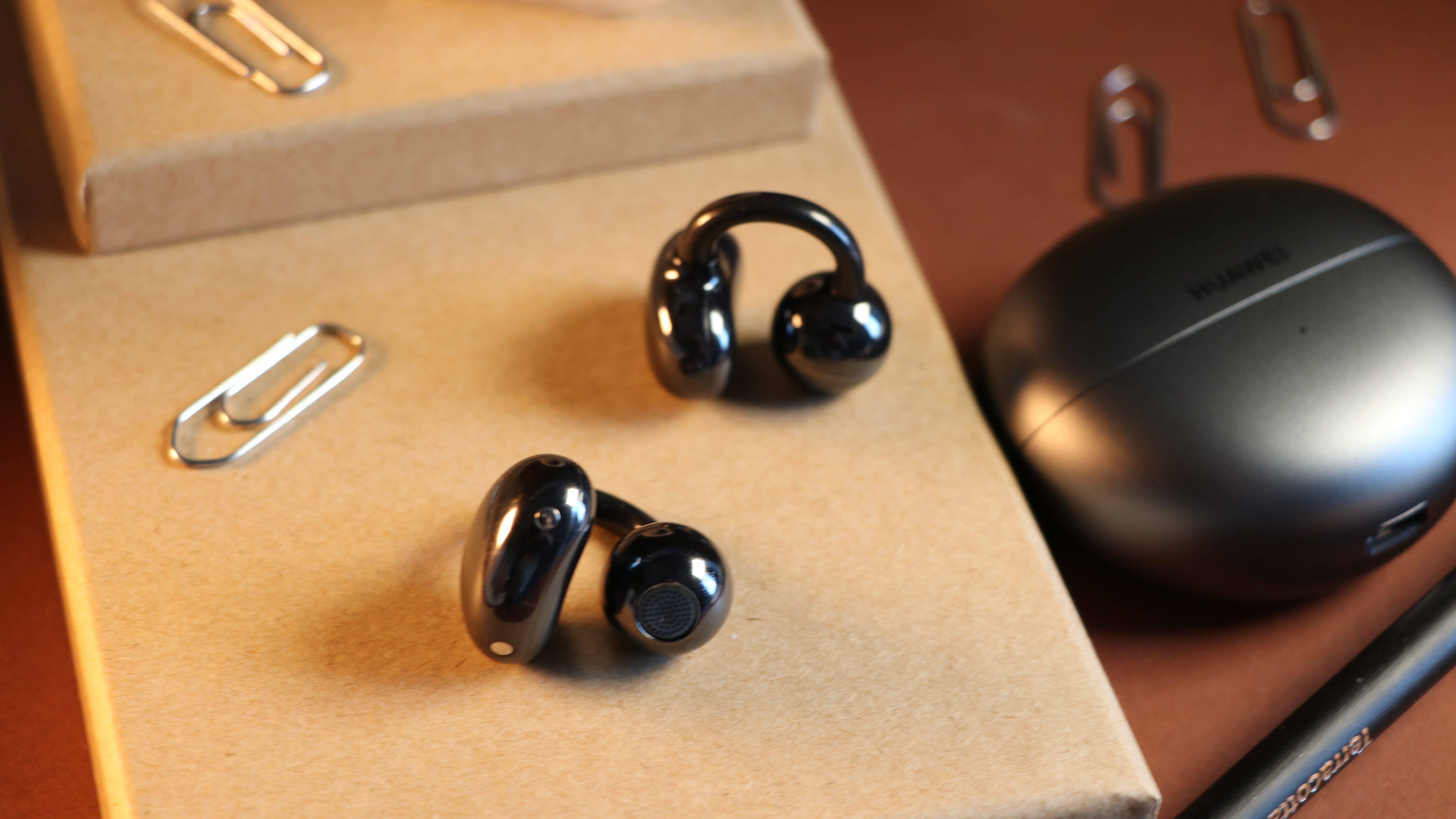 Les Huawei FreeClip posés sur un calpin avec leur boîtier de recharge posé juste à droite