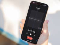 Une main tenant un Apple iPhone 16 Pro affichant un écran d'enregistrement vocal avec forme d'onde et minuterie.