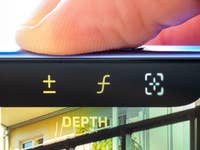 Gros plan de l'écran d'un iPhone 16 montrant des boutons d'ajustement de profondeur et le doigt d'un utilisateur au-dessus.