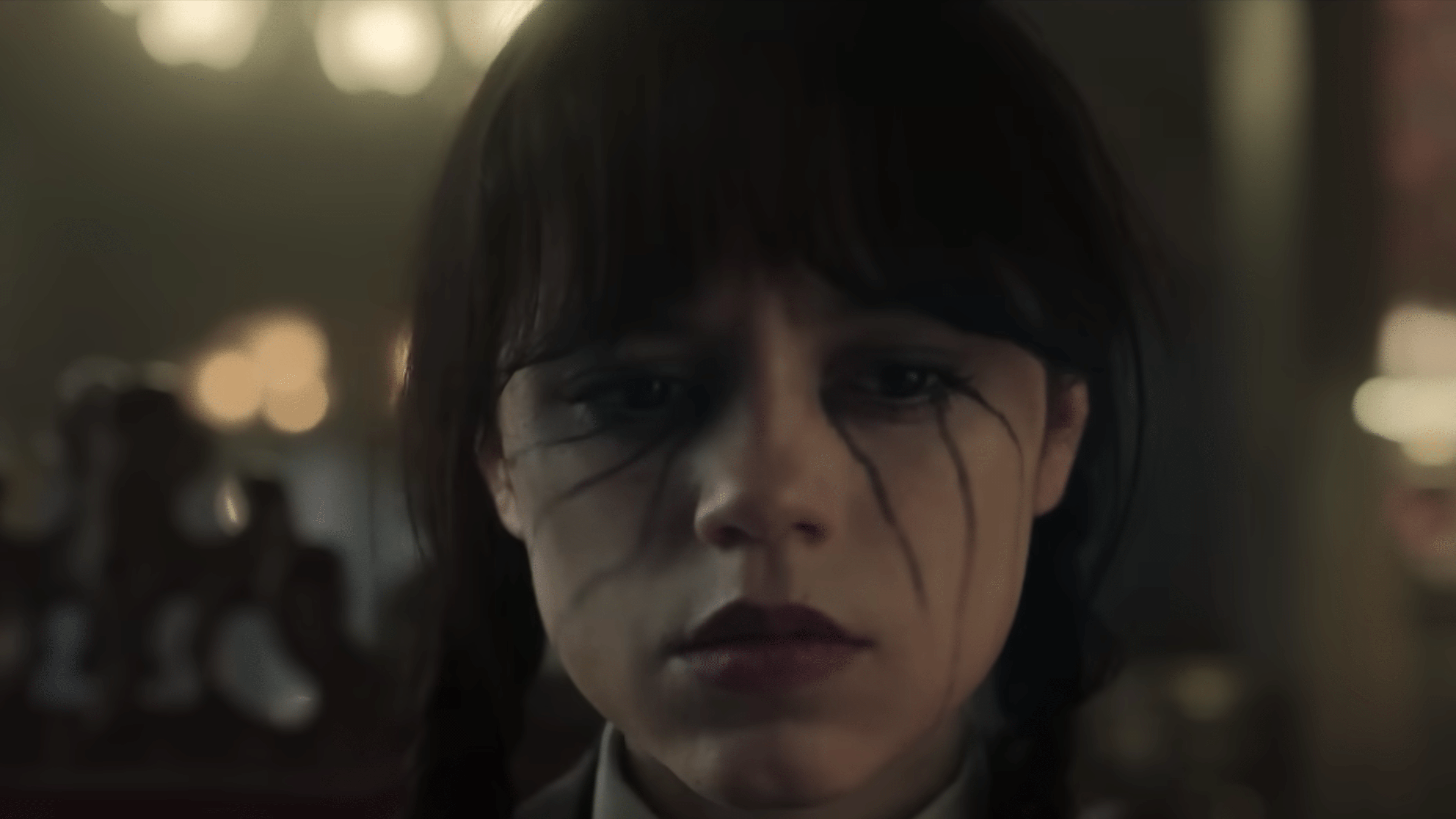 Gros plan d'une fille avec du maquillage sombre et des nattes, ayant l'air pensif.