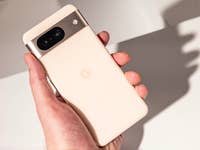 Le Google Pixel 8 vu de dos et de haut tenu dans une main gauche avec un arrière-plan blanc