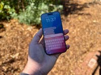 Une personne tenant un smartphone affichant une interface d'assistant numérique avec l'heure et des requêtes.